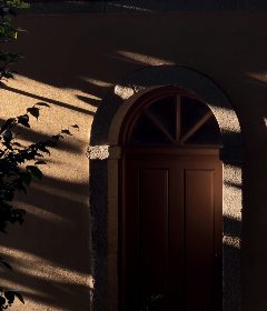 Uma porta em arco entre as sombras do fim da tarde