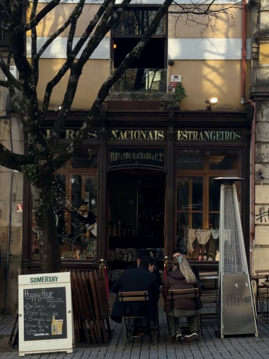 Uma antiga casa de vinhos com mesas cá fora e um quadro de ardósia