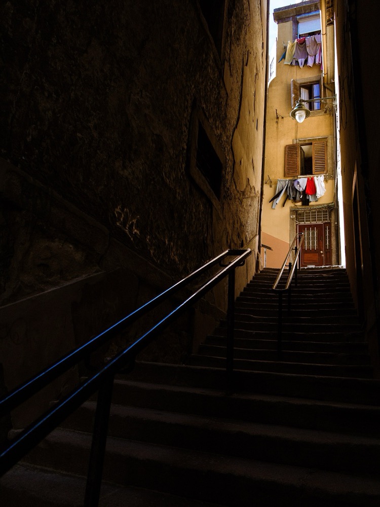 Narrow stone stairway lit by a warm window at dusk