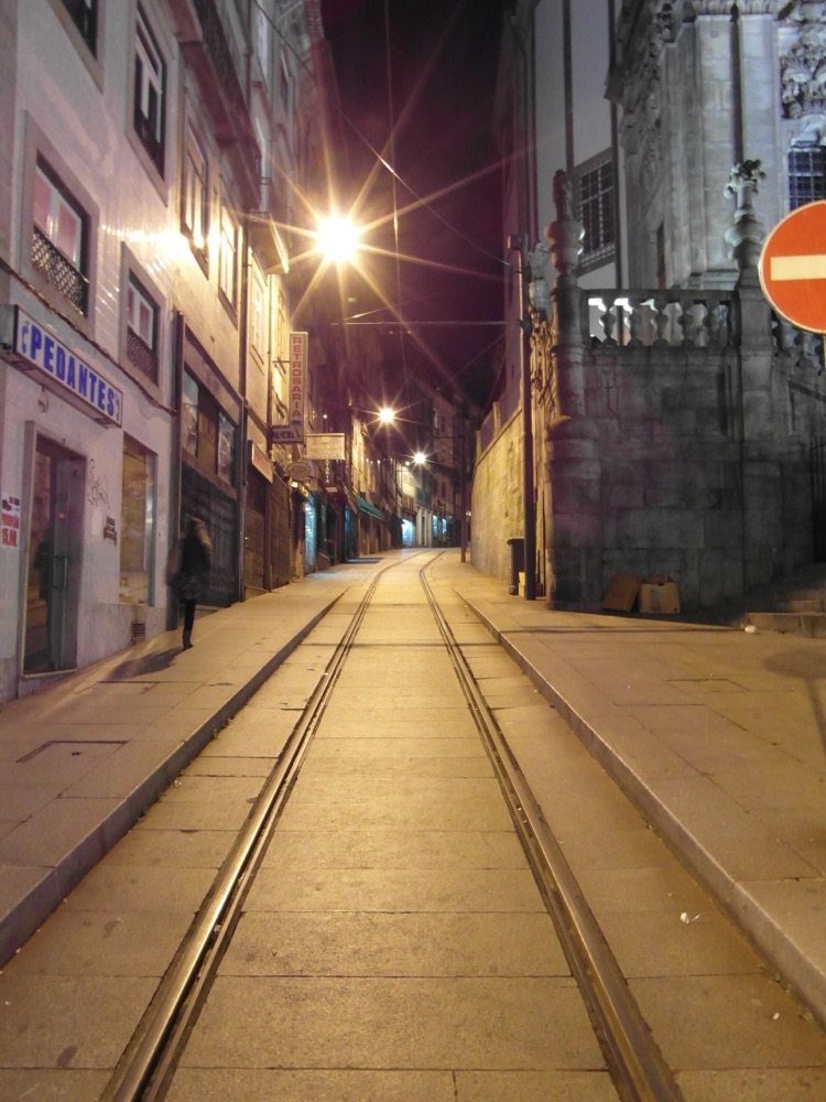 Empty tram tracks running down a Porto street at night